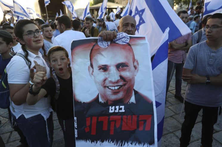 나프탈리 베네트 신임 총리를 비난하는 내용이 담긴 포스터를 들고 깃발 행진에 참가하고 있는 유대교 시민 [이미지출처=AP연합뉴스]