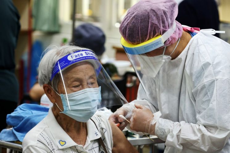 지난 15일(현지시간) 대만 북부 신베이의 한 학교에 마련된 접종소에서 한 노인이 마스크와 얼굴 가리개를 착용한 채 코로나19 백신을 접종받고 있다. [이미지출처=로이터연합뉴스]