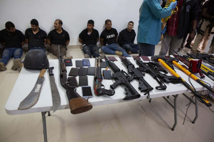 아이티 수도 포르토프랭스의 경찰청에서 지난 8일(현지시간) 언론에 공개한 대통령 암살 용의자와 이들에게서 압수한 소총·칼 등 무기의 모습. [이미지출처=연합뉴스]