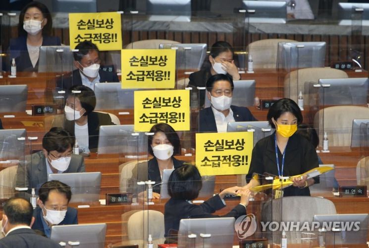 류호정 정의당 의원이 지난 1일 오후 국회 본회의에서 '손실보상 소급적용'이라고 적힌 손팻말을 나눠주고 있다. / 사진=연합뉴스