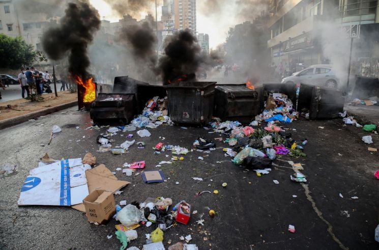 15일(현지시간) 레바논 베이루트에서 하리리 총리 지명자의 사임 직후 시민들이 반정부 시위를 진행하며 길거리의 한 쓰레기 수거함이 불에 타고 있다. [이미지출처=EPA연합뉴스]
