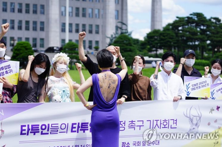 류호정 정의당 의원(뒷모습)이 6월16일 국회에서 타투인들과 함께 타투입법 제정 촉구 기자회견을 하고 있다. 이날 류 의원은 유명 타투이스트 밤이 그린 타투스티커를 등에 붙인 채 기자회견을 진행했다 [이미지출처=연합뉴스]