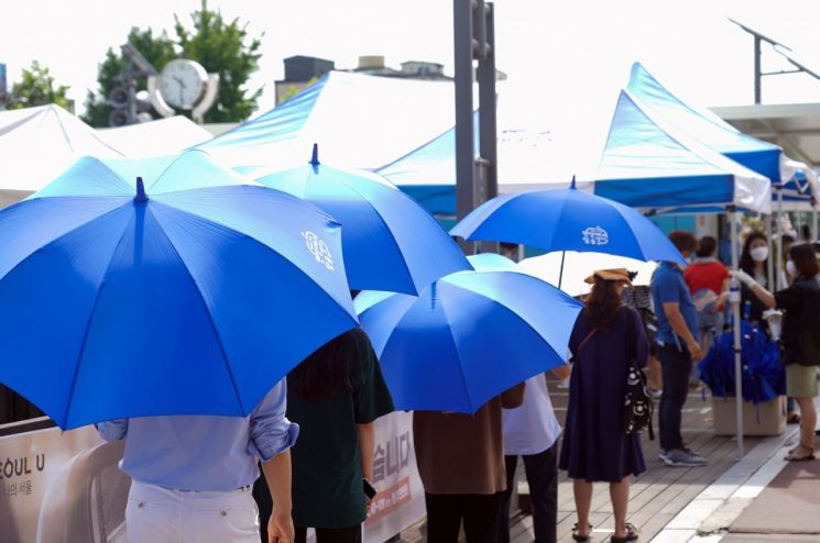 성북구청 바람마당 선별진료소를 찾은 시민들이 폭염 대피용 파란우산을 쓰고 대기하고 있는 모습