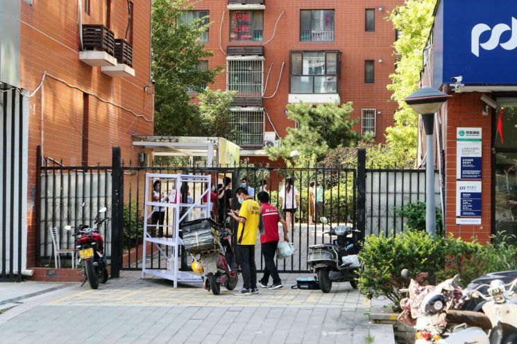 지난달 31일 코로나19 확산으로 봉쇄 조치를 당한 중국 베이징의 한 주택단지에서 택배기사가 주민들에게 물품을 전달하고 있다. (사진제공=연합뉴스)
