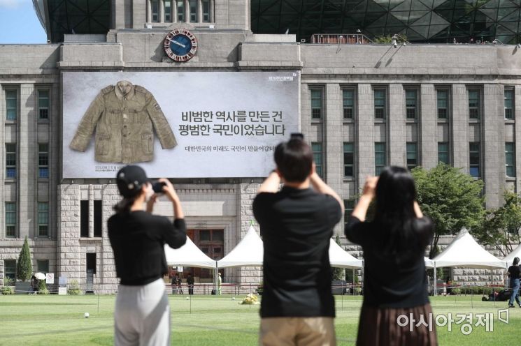 광복군 군복 옆에 '비범한 역사를 만든 건 평범한 국민이었습니다' 문구가 적혀 있다. 시민들이 꿈새김판에 걸린 광복군 군복 사진을 촬영하고 있다. /문호남 기자 munonam@