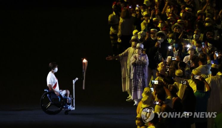 7월23일 일본 도쿄 신주쿠 국립경기장에서 열린 2020 도쿄올림픽 개막식에서 장애인올림픽 금메달리스트가 성화를 옮기고 있다. [이미지출처=연합뉴스]