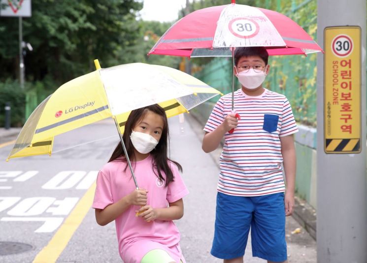 어린이들이 LG디스플레이가 준비한 '투명 안전 우산'을 쓰고 있는 모습.(사진제공=LG디스플레이)