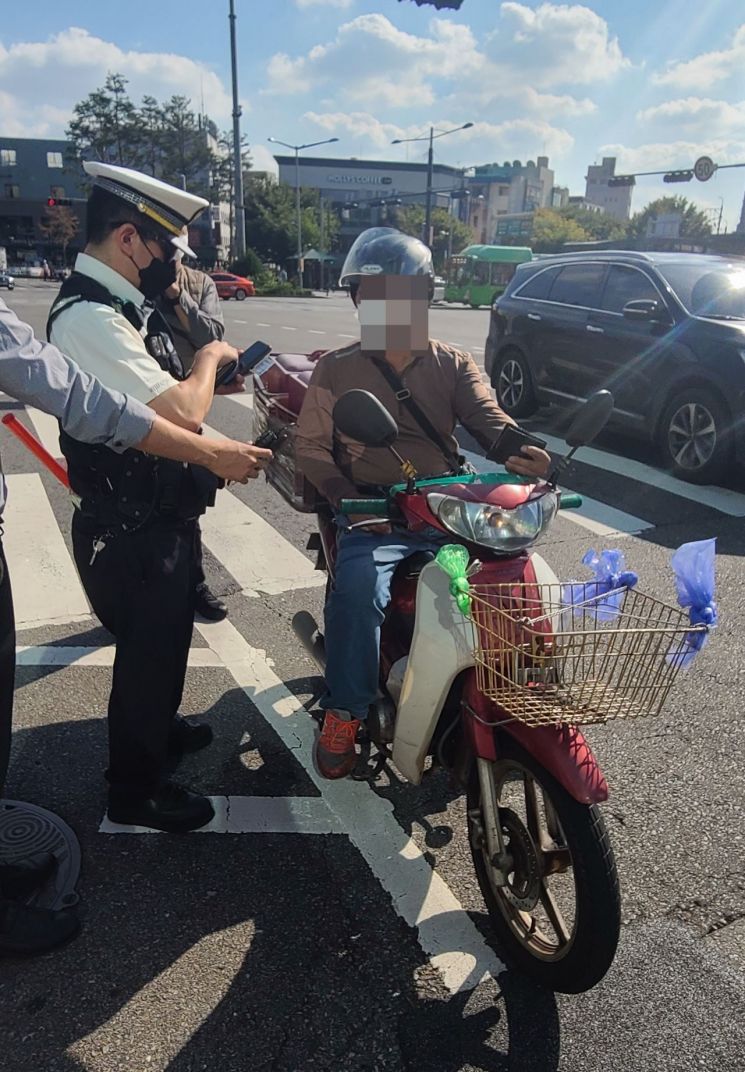 14일 오후 서울 마포구 합정역 인근에서 경찰이 불법 차선 변경을 한 오토바이 운전자를 단속하고 있다.