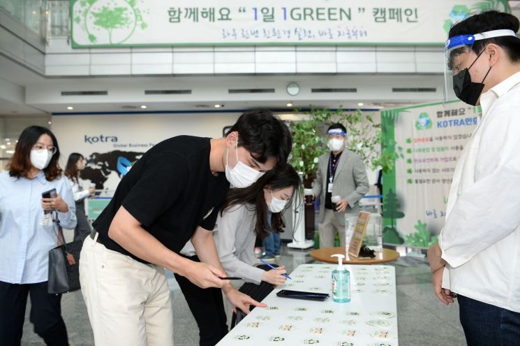 KOTRA가 지속가능경영위원회를 개최해 KOTRA ESG 경영을 선포했다. KOTRA 직원들이 '1일 1Green' 친환경 실천을 서약하고 약속 나무에 서약카드를 걸고 있다./사진제공=KOTRA