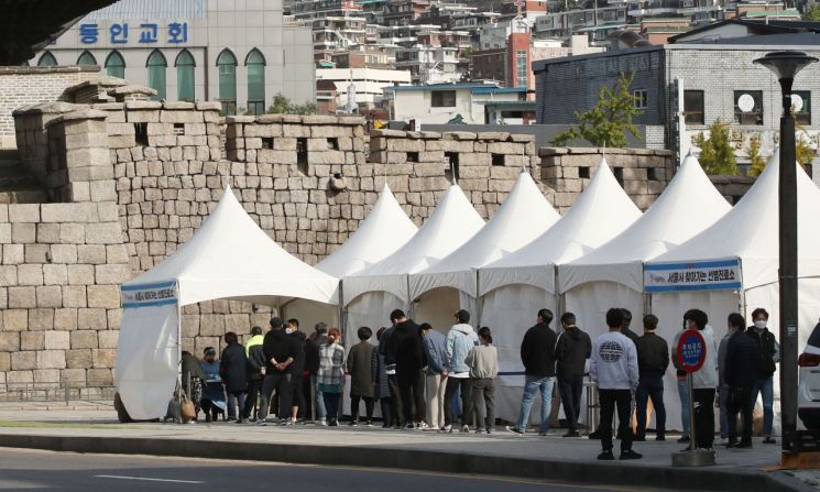 지난 18일 오전 서울 종로구 흥인지문 옆에 설치된 찾아가는 선별검사소에서 코로나19 집단감염이 발생한 동대문 인근 시장 종사자들이 검사를 받기 위해 대기하고 있다. [이미지출처=연합뉴스]