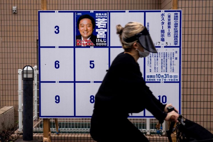 기시다 후미오 총리 내각의 신임을 묻는 일본 중의원 선거(총선)가 지난 19일 후보 등록과 함께 막이 오른 가운데 도쿄 시내에 나붙은 집권 자민당 지역구 후보의 선거 벽보 앞으로 자전거를 탄 행인이 지나가고 있다. [이미지출처=연합뉴스]