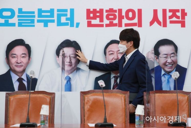 이준석 국민의힘 대표가 1일 국회에서 열린 최고위원회의에 참석하면서 배경판에 나온 대선 경선 후보자들의 얼굴을 살펴보고 있다./윤동주 기자 doso7@