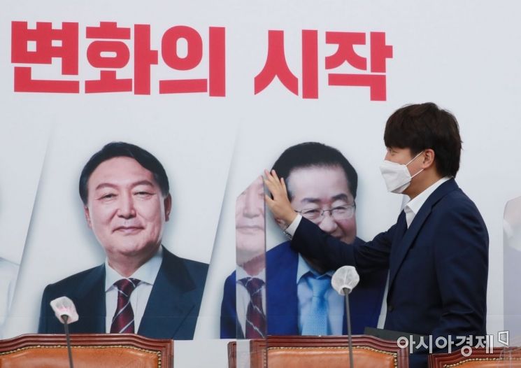 이준석 국민의힘 대표가 1일 국회에서 열린 최고위원회의에 참석하면서 배경판에 나온 대선 경선 후보자들의 얼굴을 살펴보고 있다./윤동주 기자 doso7@