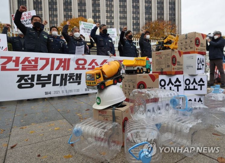 건설기계 노동자들이 9일 오전 정부서울청사 앞에서 전국건설노동조합 주최로 열린 기자회견에서 요소수 품귀 사태로 생계를 위협받고 있다며 문제 해결을 촉구하는 내용의 구호를 외치고 있다. [이미지출처=연합뉴스]