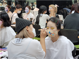 한 학생이 마스크에 메이크업을 해주고 있다.