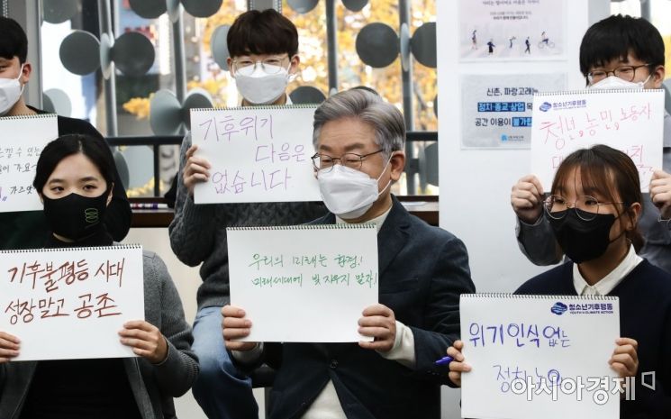 이재명 더불어민주당 대선후보가 16일 서울 서대문구 청년문화공간 신촌 파랑고래에서 열린 청소년 청년 기후활동가들과 기후위기 간담회에 참석, 행사 시작에 앞서  구호가 적힌 손팻말을 들고 포즈를 취하고 있다./국회사진기자단