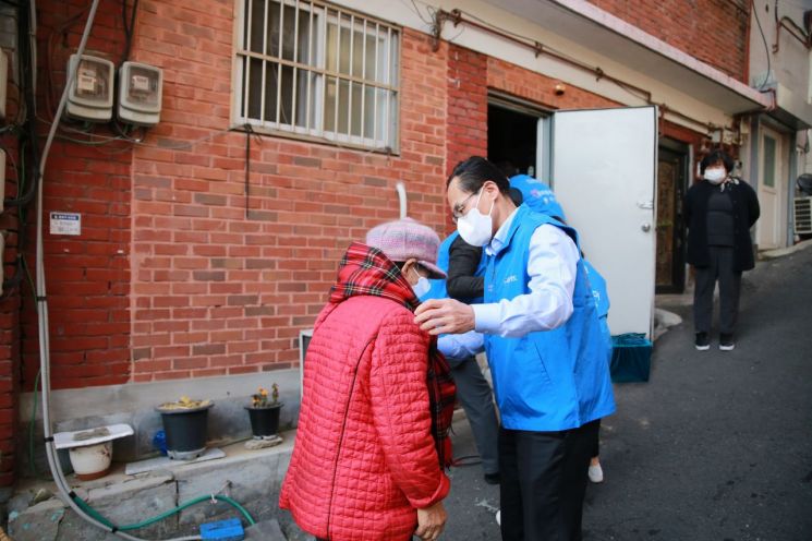 29일 창신 2동에서 진행된 김장김치 전달 행사에서 김정기 우리카드 대표이사(오른쪽)가 주민에게 목도리를 걸어주고 있다.