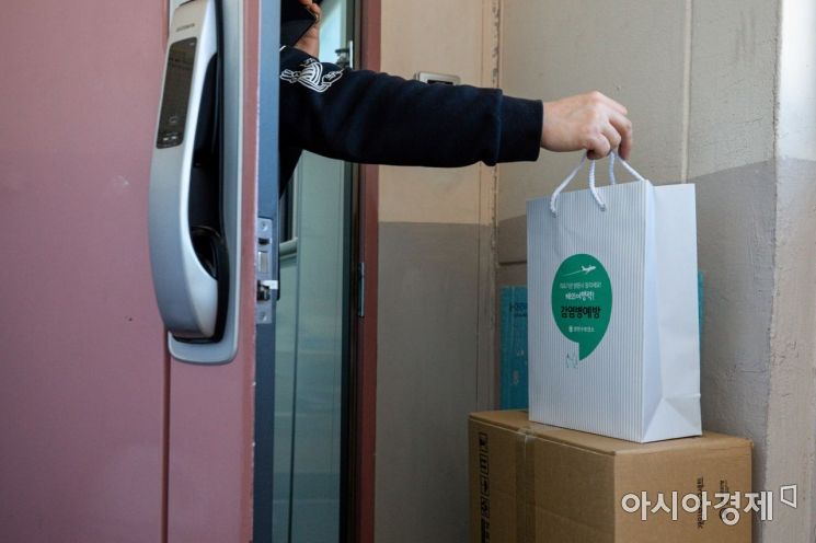 서울 양천구 한 아파트에서 재택치료 중인 확진자가 양천구코로나19재택치료전담팀이 전달한 '재택치료키트'를 수령하고 있다./강진형 기자aymsdream@