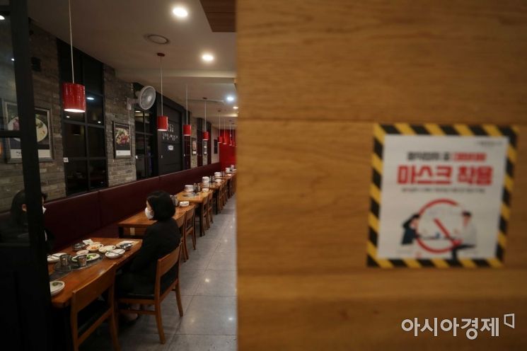 서울 중구 한 식당에 붙은 마스크 착용 안내 스티커 뒤로 시민들이 식사를 하고 있다. /문호남 기자 munonam@