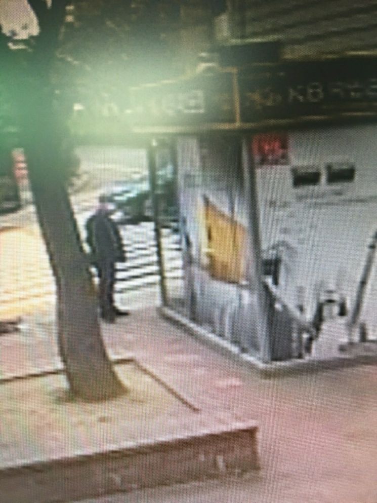 부산 연산동의 한 은행 ATM 부스 앞에서 지난 15일 부스터샷을 맞기 위해 병원으로 가던 정찬오 경감이 현금을 전송하던 보이스피싱범을 발견하는 모습이 CCTV에 찍혔다. [이미지출처=부산경찰청]