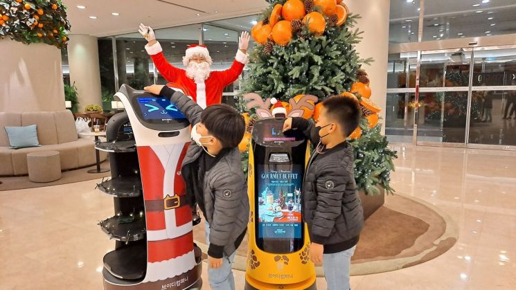 켄싱턴리조트 서귀포 메인 로비에서 어린이 고객들이 '산타 로봇'이 안내하는 리조트의 이벤트 정보를 확인하고 있다.