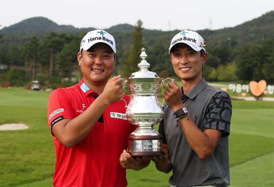 Ham Jung-woo (left) and caddy Kim Yong-hyun smile brightly while holding the trophy just after winning the Hyundai Marine & Fire Insurance Choi Kyung-ju Invitational last October.