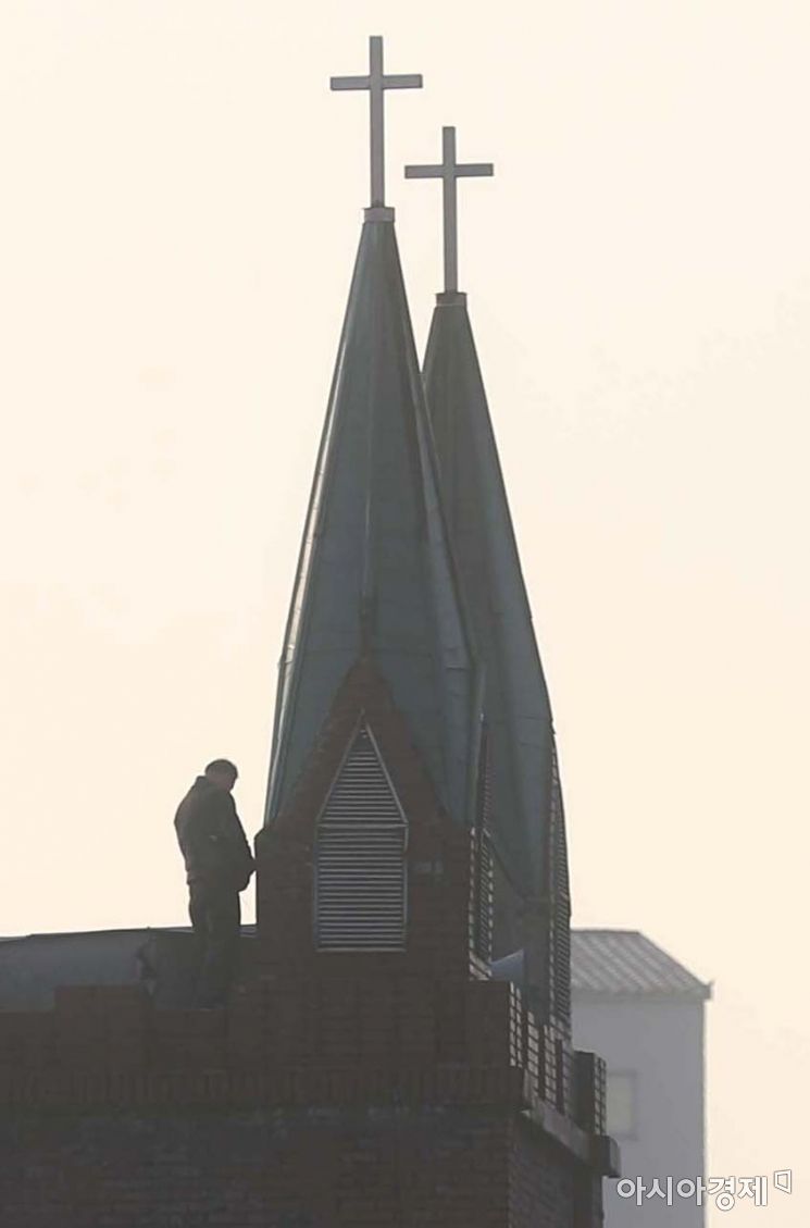 ＜이달의보도사진상 - 우수상＞ 지붕에 올라 명도집행 인력과 대치중인 사랑제일교회의 한 교인이 교회 십자가 철탑 옆에서 소변을 누고 있다. 철거 문제를 두고 재개발 조합과 갈등을 빚어온 서울 성북구 사랑제일교회에 대해 법원이 15일 새벽 6차 명도집행에 나섰지만 교인들의 반발로 또다시 무산됐다. 지난 5일 5차 명도집행이 무산된 데 이어 10일 만이다. 교인들은 소화기 분말을 분사하고 돌과 타이어를 던지는 등 거센 저항을 했다. 전봇대와 지붕 위에 올라 농성을 벌이기도 했다. 현장에 나온 전광훈 담임목사는 "이건 헌법과 대한민국에 대한 도전"이라며 "앞으로도 교회를 재탈환할 것"이라고 주장했다. 장위10구역 한복판에 있는 사랑제일교회는 재개발 조합 측의 보상금이 충분하지 않다며 철거를 거부하고 있다. ＜문호남기자/ 아시아경제＞