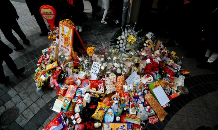 24일 승용차 돌진 사고로 할머니와 손녀 목숨을 앗아간 부산 수영구 수영팔도시장 입구 사고현장에 시민들이 자발적으로 쌓아둔 추모 국화꽃과 인형, 목도리, 과자 등 각종 추모 물품이 대형 하트를 만들고 있다. [이미지출처=연합뉴스]