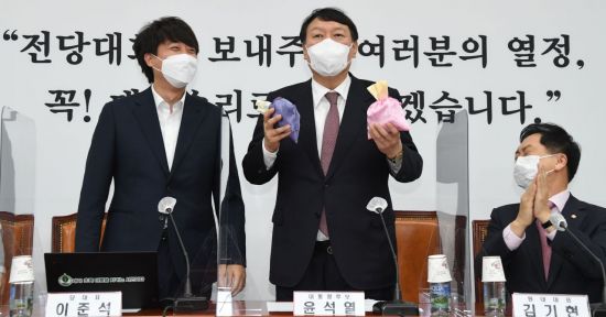 윤석열 국민의힘 대선 후보(가운데)가 지난달 8일 오전 서울 여의도 국회에서 열린 최고위원회의에서 이준석 대표(왼쪽)로부터 비단주머니를 받고 발언하고 있다. / 사진=연합뉴스