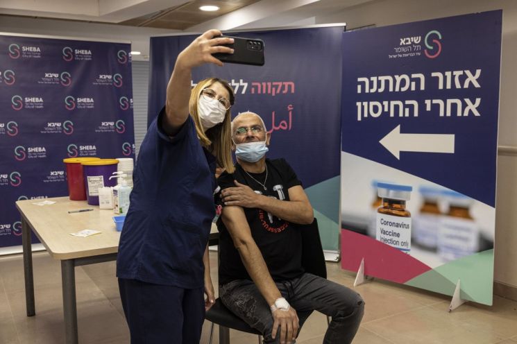 이스라엘 서부 라마트간의 셰바 메디컬 센터에서 한 남성이 화이자 코로나19 백신 4차 접종을 하고 간호사와 함께 기념 '셀카'를 촬영하고 있다. [이미지출처=AP연합뉴스]
