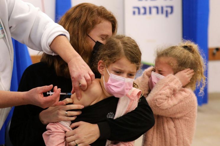 오미크론 코로나19 변이가 급속히 번지고 있는 이스라엘 중부 모디인에서 지난 2일(현지시간) '클라리트 건강 서비스'(CHS) 의료진이 한 어린이에게 화이자-바이오엔테크의 코로나19 백신을 접종하고 있다. [이미지출처=연합뉴스]