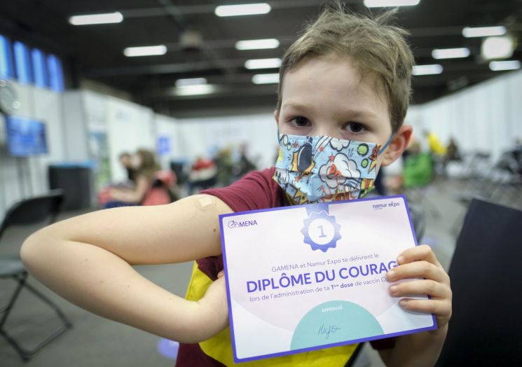 지난달 19일(현지시간) 벨기에 남부 나무르의 코로나19 백신 접종소에서 6살 어린이가 화이자 코로나19 백신 1차 접종을 마친 뒤 증명서를 들어 보이고 있다. [이미지출처=연합뉴스]