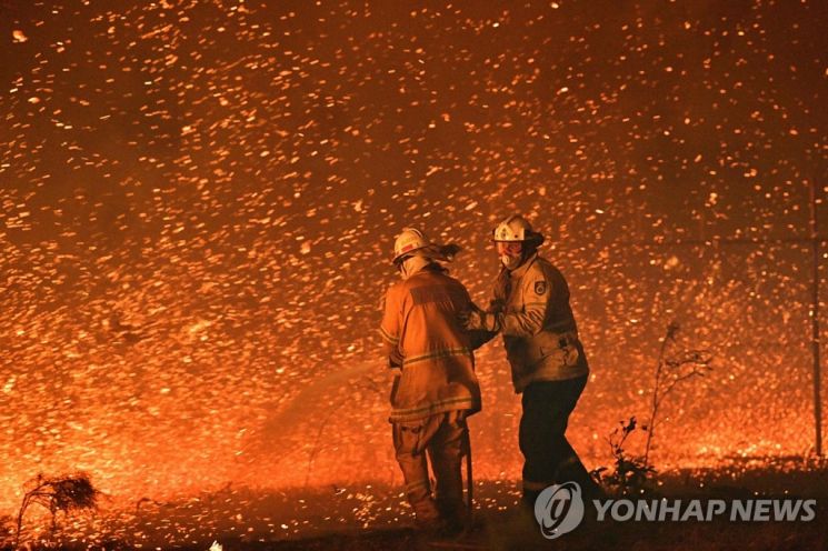 지난 2019년 말 호주 뉴사우스웨일스주의 나우라 인근에서 발생한 산불이 강풍을 타고 번지는 모습. 소방관들이 주거지역을 향하는 불길을 막기 위해 노력하고 있다. / 사진=연합뉴스