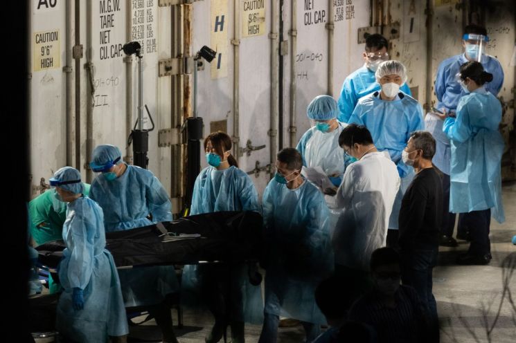 홍콩이 코로나19 환자 폭증으로 영안실 부족 사태에 처한 가운데 사망자의 시신들이 영구차에서 냉동 해운 컨테이너로 옮겨지고 있다. [이미지출처=연합뉴스]