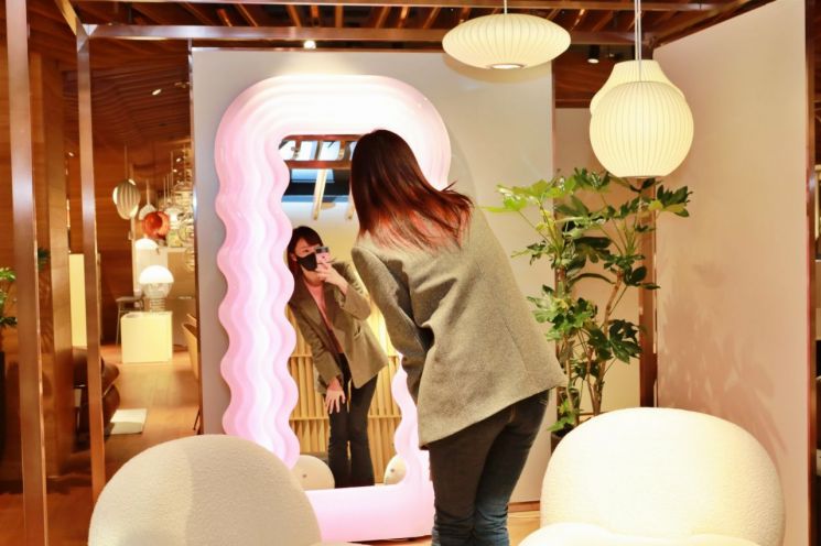 모델이 롯데백화점 본점 라이프스타일 편집숍 '카인드 스페이스'에 설치된 '울트라프라골라 거울'을 살펴보고 있다.
