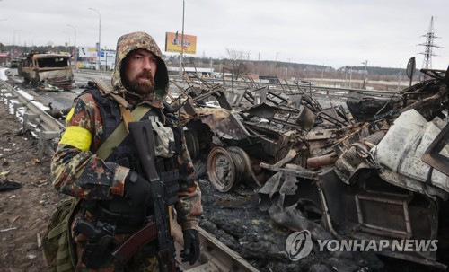 지난 1일(현지시간) 파손된 러시아군 차량 옆에 무장한 병사가 서있다. / 사진=연합뉴스