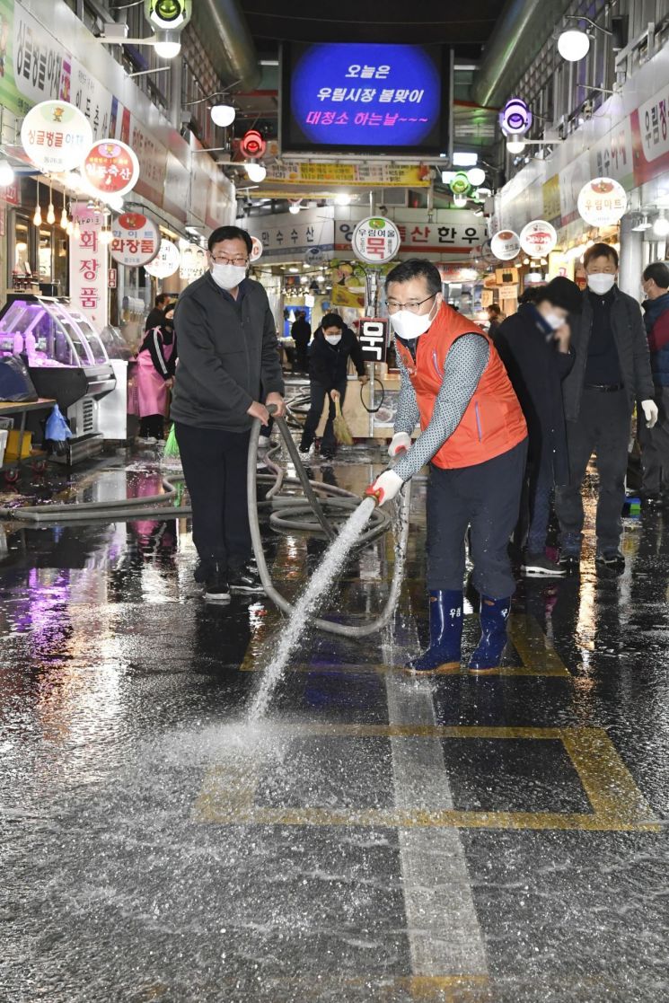 류경기 중랑구청장이 28일 오후 8시 우림골목시장 상인들과 함께 시장에서 봄맞이 물청소를 하고 있다.