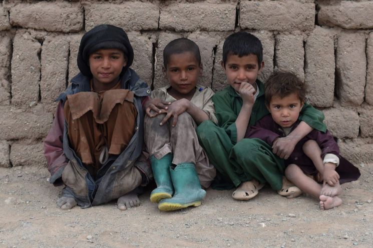 아프가니스탄 중서부 헤라트주의 한 난민캠프에서 어린이들이 벽돌로 지어진 임시 가옥 앞에 앉아 있다. [이미지출처=연합뉴스]