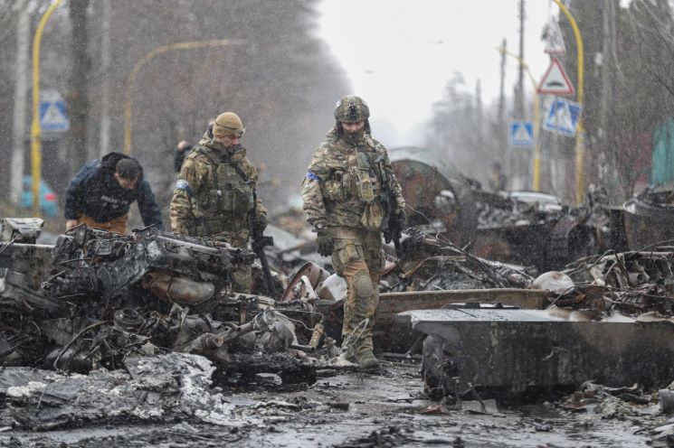 우크라이나 수도 키이우(키예프) 외곽 도시 부차에서 3일(현지 시각) 병사들이 길거리에 파괴된 채 널브러진 러시아군 탱크와 장갑차, 군용차량 잔해를 살펴보고 있다. [사진=연합뉴스]