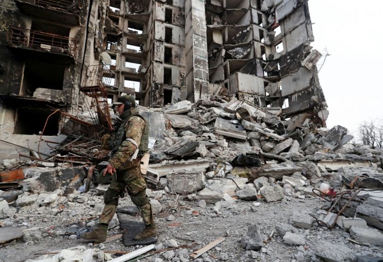 우크라이나 남부 항구도시 마리우폴에서 친(親)러시아 반군 병사가 무차별 폭격으로 뼈대만 남은 아파트 앞을 지나고 있다. [이미지출처=연합뉴스]
