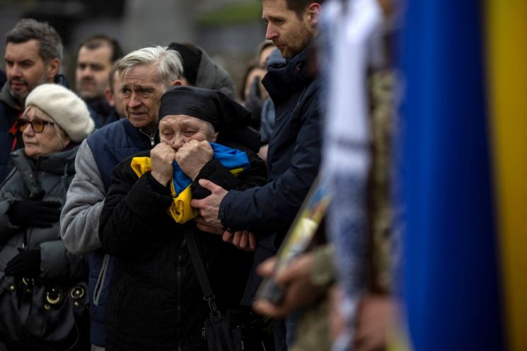 우크라이나 서부 도시 르비우의 공동묘지에서 지난 2일(현지시간) 한 여성이 러시아군과 전투를 벌이다 숨진 아들 장례식에서 관에 덮었던 국기를 껴안고 오열하고 있다. [이미지출처=연합뉴스]