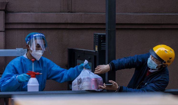 중국 상하이에서 배달원이 코로나19 확산 방지를 위해 봉쇄 조처가 내려진 주거단지의 보안요원에게 음식을 전달하고 있다. [이미지출처=연합뉴스]
