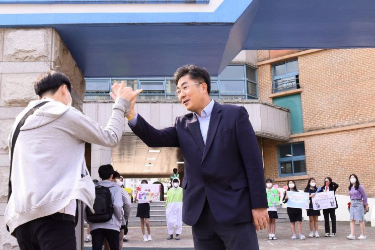 성기선 경기교육감(오른쪽) 후보가 19일 수원 칠보중학교를 찾아 등교하는 학생과 하이파이브를 하고 있다.