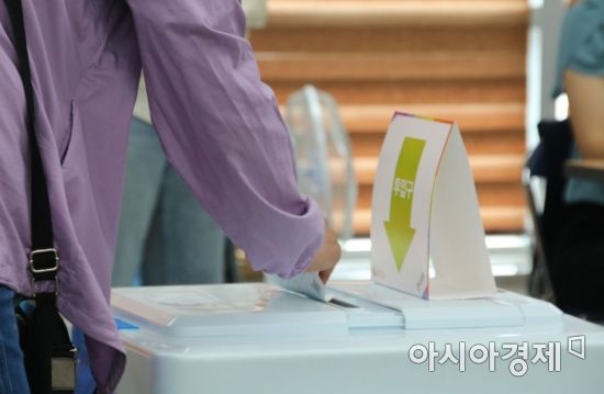 광주광역시 북구 신용동 행정복지센터에 마련된 6.1 지방선거 사전투표장에서 한 시민이 투표함에 투표용지를 넣고 있다.