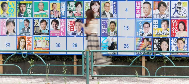지난해 7월10일 오후 도쿄도 스미다구에 설치된 후보자 안내판 앞으로 한 여성이 지나가고 있다. [이미지출처=연합뉴스]