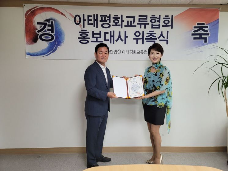 가수 문희옥(오른쪽)씨가 7월 12일 안부수 아태평화교류협회 협회장과 홍보대사 위촉식을 갖고 있다.
