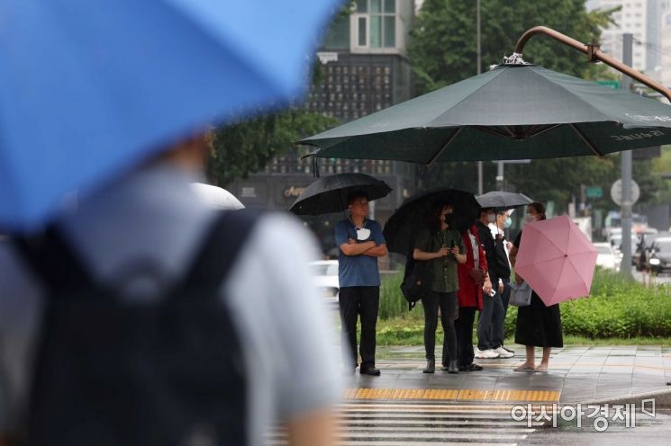 전국에 장맛비가 내린 13일 서울 광화문 사거리에서 출근길 시민들이 대형 그늘막 아래 보행 신호를 기다리고 있다. /문호남 기자 munonam@