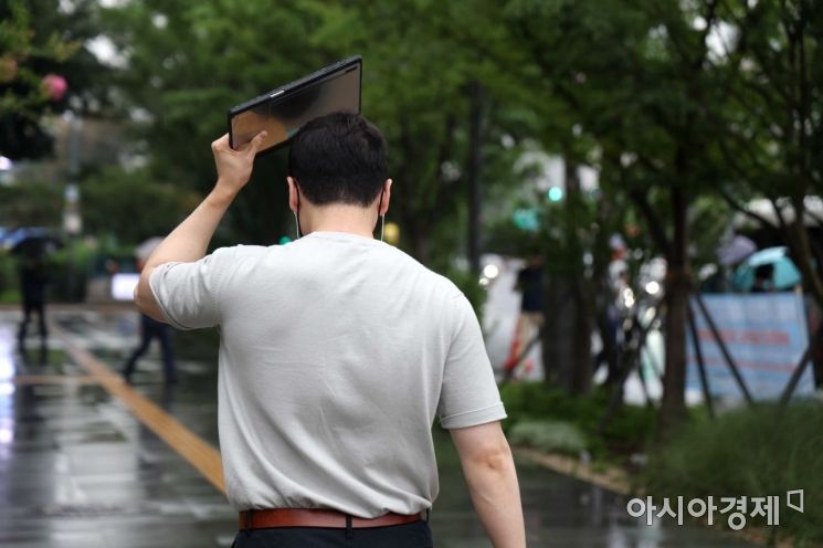 전국에 장맛비가 내린 13일 서울 광화문 사거리에서 출근길 시민이 태블릿으로 비를 막고 있다. /문호남 기자 munonam@