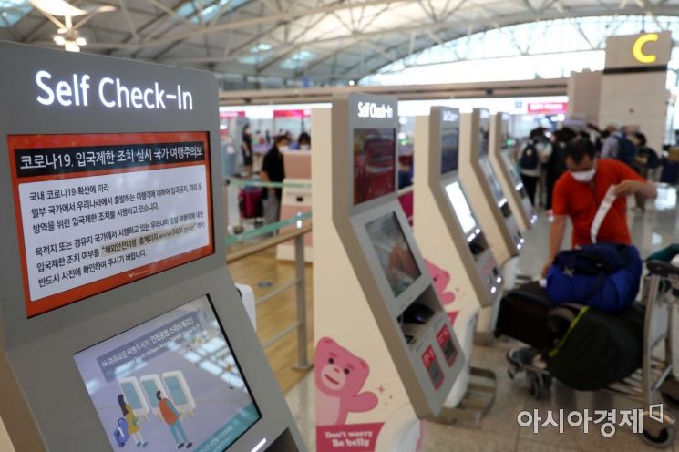 13일 인천국제공항 제1여객터미널 출국장에서 이용객이 셀프 체크인을 하고 있다. 체크인 기계에 코로나19 입국제한 조치 실시 국가 여행주의보 관련 안내가 나오고 있다. /문호남 기자 munonam@