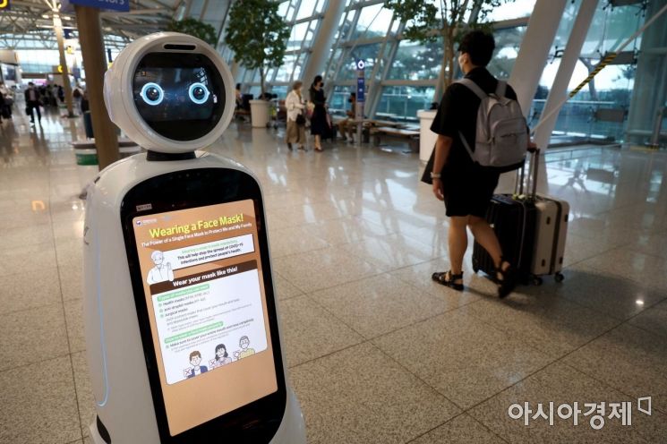 코로나19 재확산 우려가 커지고 있는 13일 인천국제공항 제1여객터미널 출국장에서 로봇 에어스타가 이용객들을 안내하고 있다. 에어스타 안내판에 마스크 착용 글귀가 떠 있다. /문호남 기자 munonam@